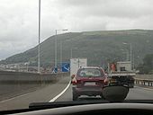 M4 at Port Talbot. This is an elevated motorway with a 50mph speed restriction as it passes over a dense urban area hemmed in by mountains to the north and the sea to the south. This photo is of the M4 at Taibach. - Coppermine - 7383.jpg